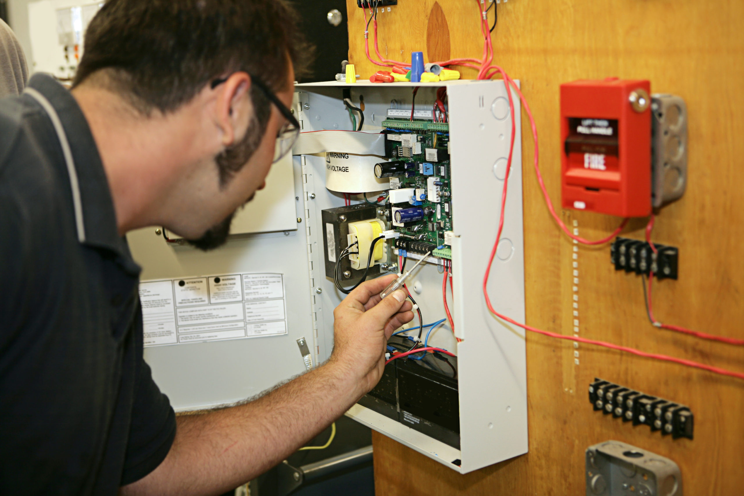 A student electrician wiring a fire alarm system at his technical college.